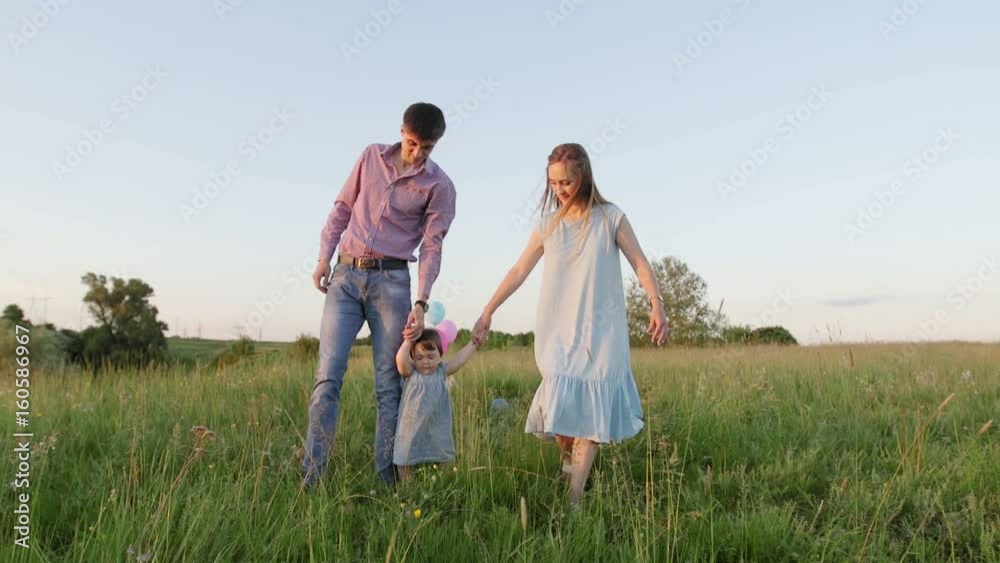 little girl walking on the green field with their parents, holding the hand of his father, slow motion little girl walking on the green field with their parents, holding the hand of his father, slow motion