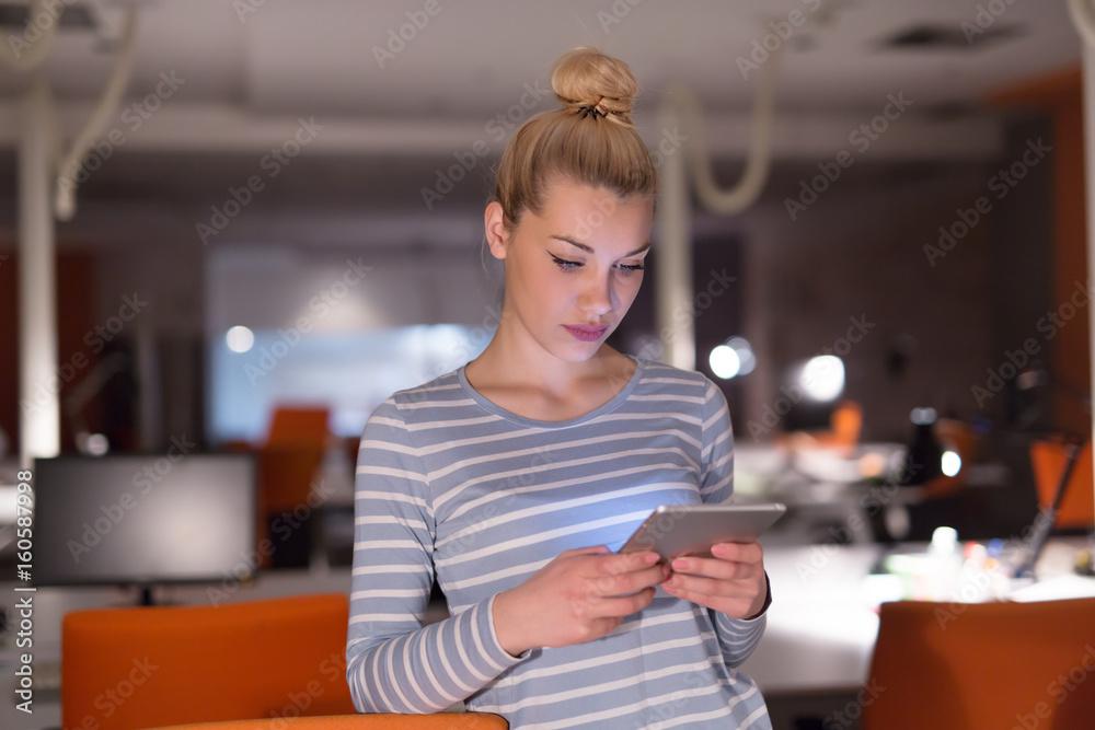 woman working on digital tablet in night office