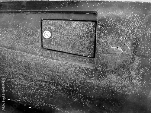 Abschließbare Tankklappe im rostigen und vergilbten Kotflügel eines italienischen Sportwagen der Sechzigerjahre als Scheunenfund in Lage bei Detmold in Ostwestfalen-Lippe, fotografiert in Schwarzweiß photo