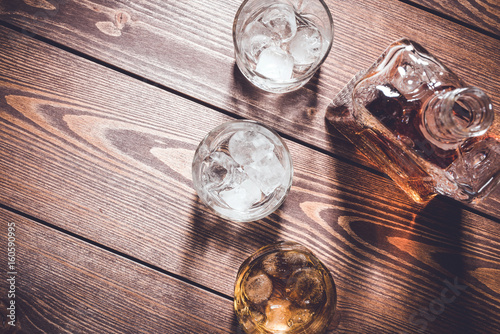 Whiskey bottle and whiskey glasses with ice cubes. Top view