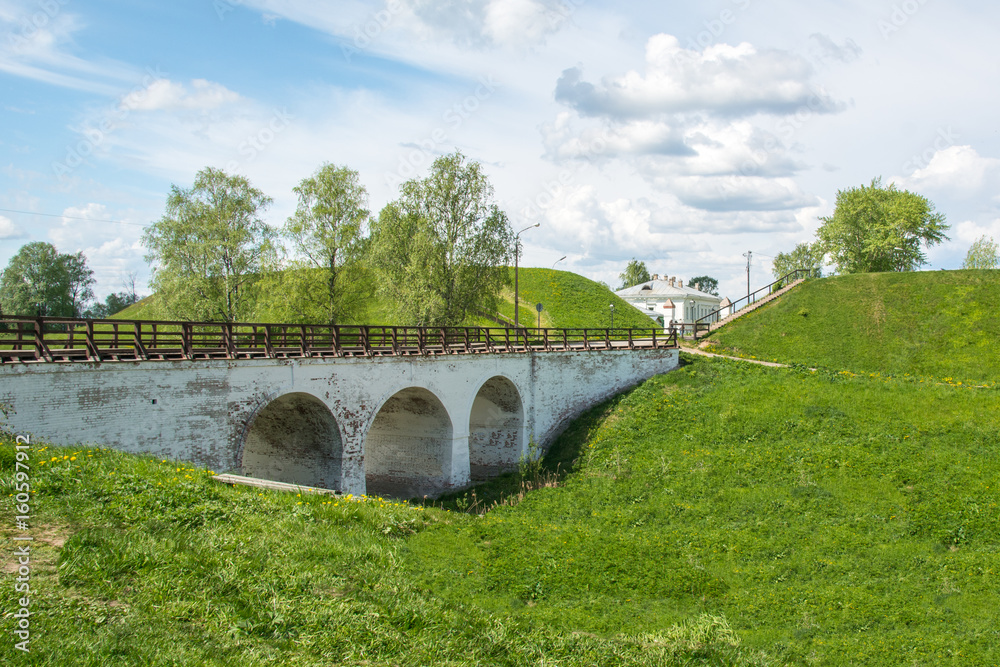 Old arched bridge over the moat and earthen ramparts. Belozersky Kremlin, Vologda region, city of Belozersk