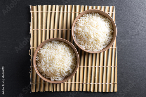 Top view: steamed cooked basmati rice in round ceramic bowls over black stone