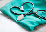 A stethoscope shaping a heart and a clipboard on a medical uniform, closeup