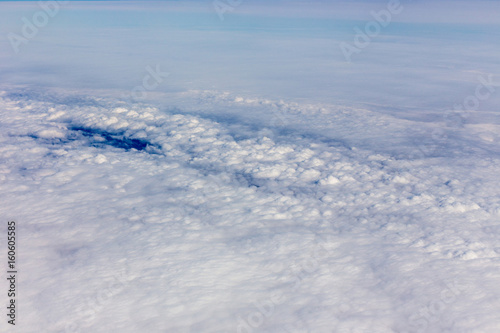 Above view of white clouds and a horizon with a blue sky.