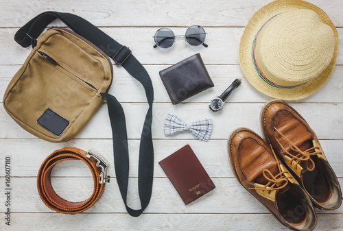 Top view accessories to travel with man clothing concept. bow tie,wallet on wooden background.watch,sunglasses,bag,hat,belt and shoes on wood table.