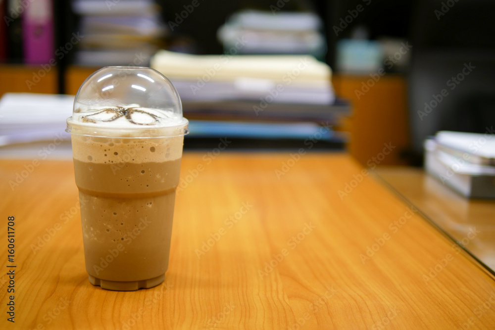 Mocha frappe in a clear plastic glass on a wooden desk in an office, selective focus Mocha frappe in a clear plastic glass on a wooden desk in an office, selective focus