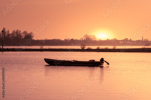 boat on River at Sundown while sun passing skyline in evening