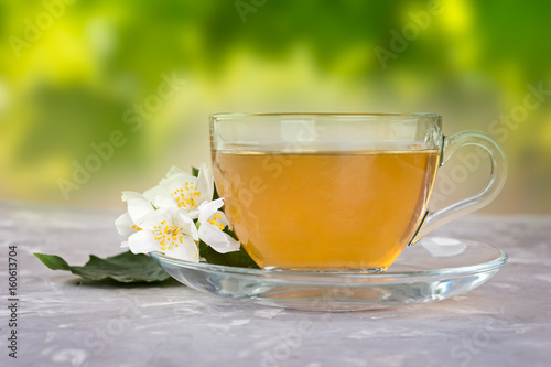 Jasmine tea with jasmine flowers on a grey stone table.