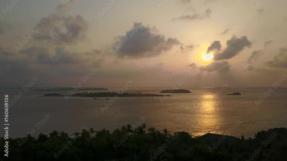 Aerial view of tropical island on sunset, camera is accending over silhouettes of palms and ocean Aerial view of tropical island on sunset, camera is accending over silhouettes of palms and ocean