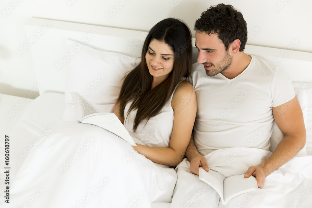 Young couple reading a book in the bed Young couple reading a book in the bed