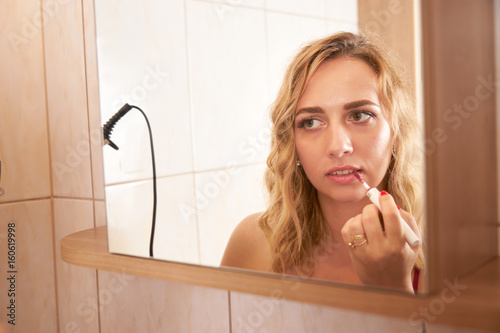 A reflextion of woman coloring her lips.