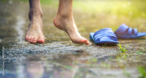 Barefoot the feet of the boy and ankle in a mud puddle. © kulkann