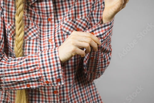 Woman rolling up the sleeves in checked shirt