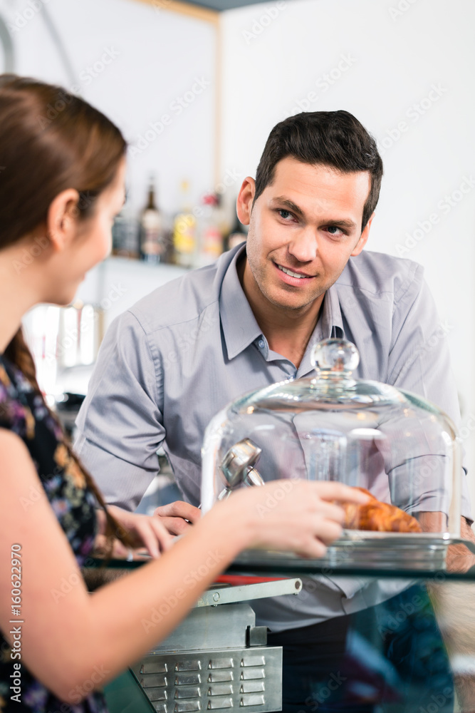 Friendly waiter offering to young female customer fresh French croissants for breakfast Friendly waiter offering to young female customer fresh French croissants for breakfast