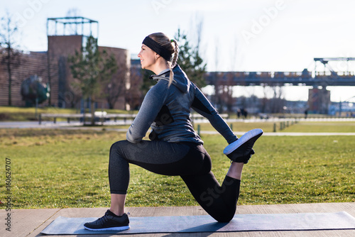 Valokuva Young woman stretching her quadriceps muscles by grabbing her ankle during outdo