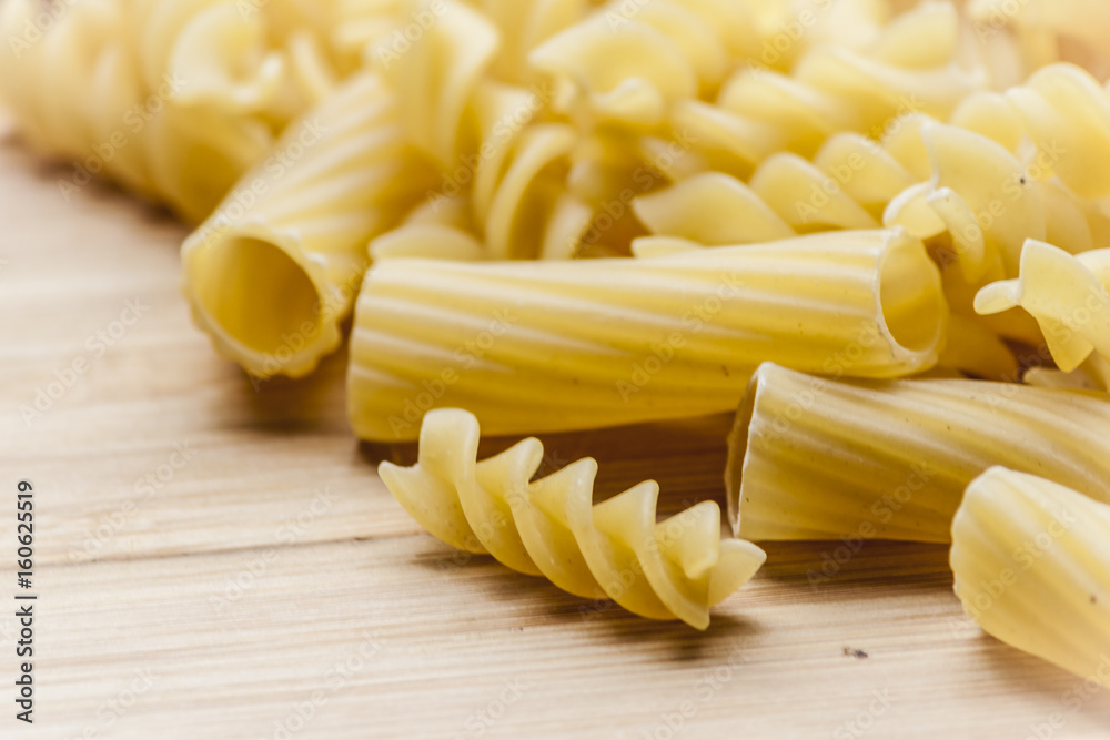 Italian pasta: rigatoni and fusilli are on a wooden table Italian pasta: rigatoni and fusilli are on a wooden table
