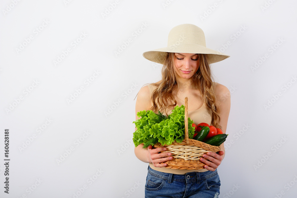 Beautiful young woman holding a basket of vegetables, on white background, copy space
