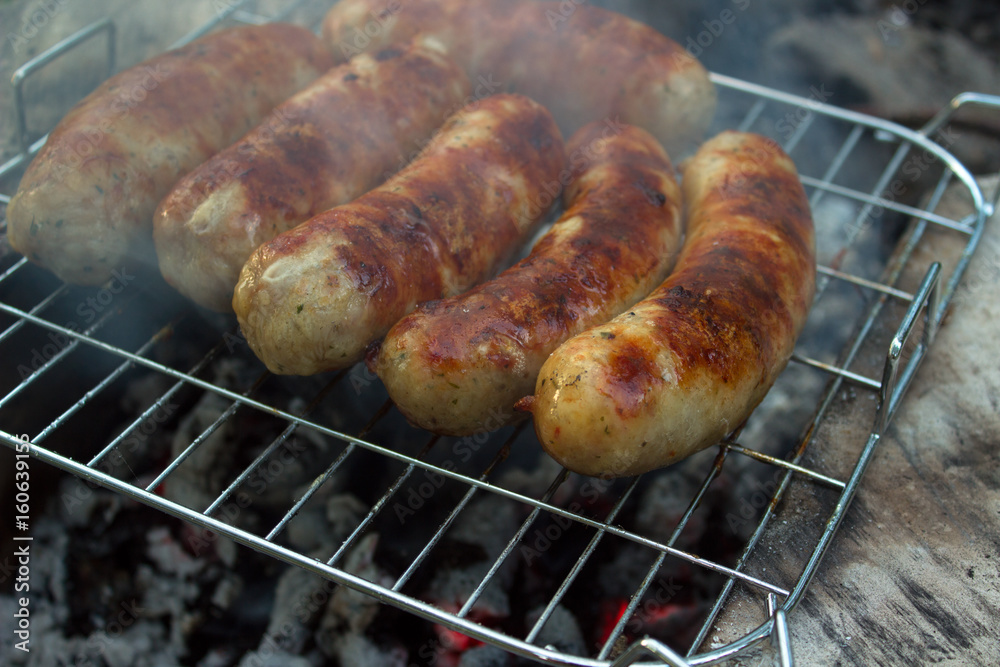 Pork sausage is fried on a charcoal with smoke on the grate Pork sausage is fried on a charcoal with smoke on the grate