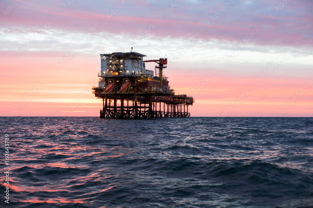 Silhouette of offshore oil platform at sunset 