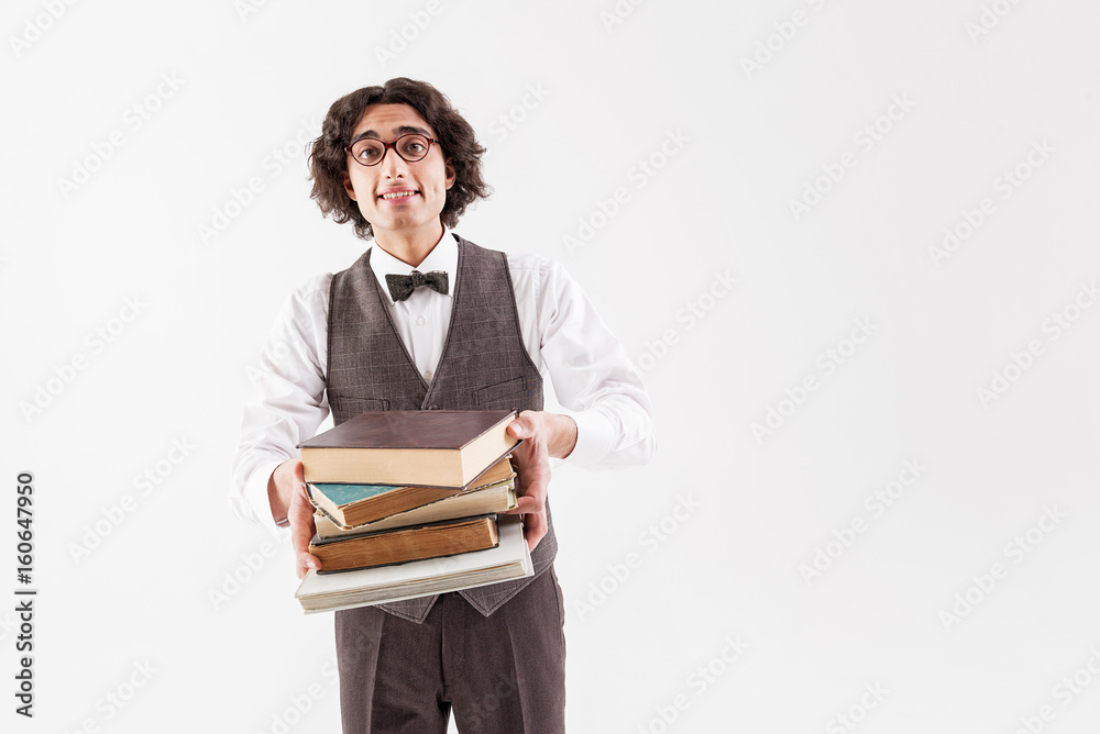 Cheerful clever student holding heap of volumes Cheerful clever student holding heap of volumes