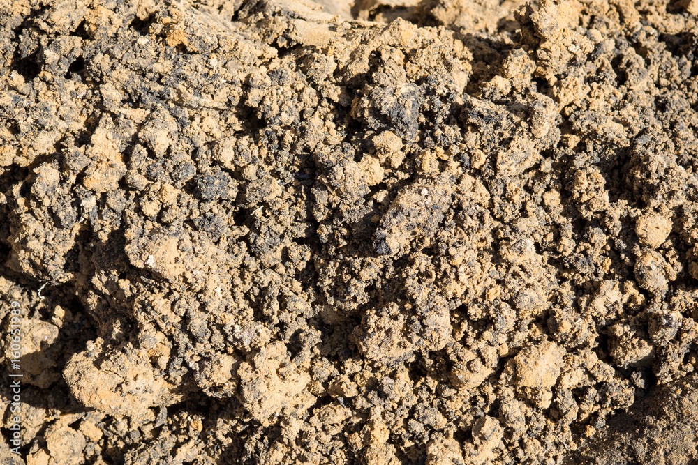The texture is lumpy wet pit sand . The background of the industrial sand for construction works. Natural material for bricks and concrete products.