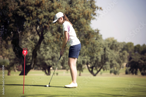 young girl playing golf on a sunny day