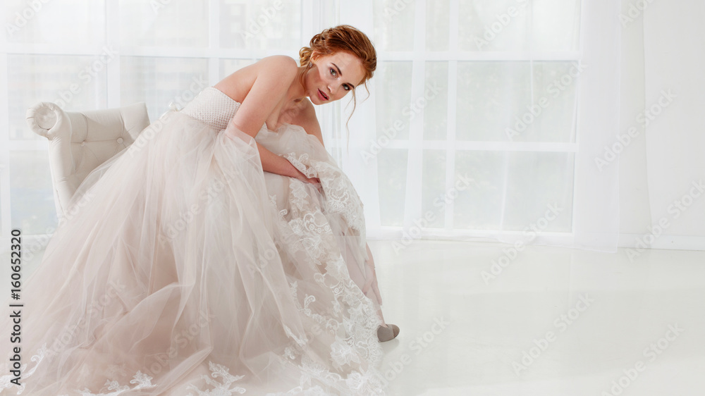Portrait of a beautiful girl in a wedding dress. Bride in luxurious dress sitting on a chair Portrait of a beautiful girl in a wedding dress. Bride in luxurious dress sitting on a chair