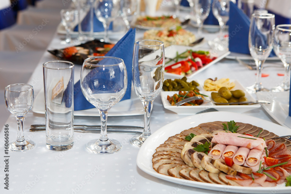 Served with Cutlery and food on table. A Banquet with food and snacks with a luxurious setting on a white tablecloth.