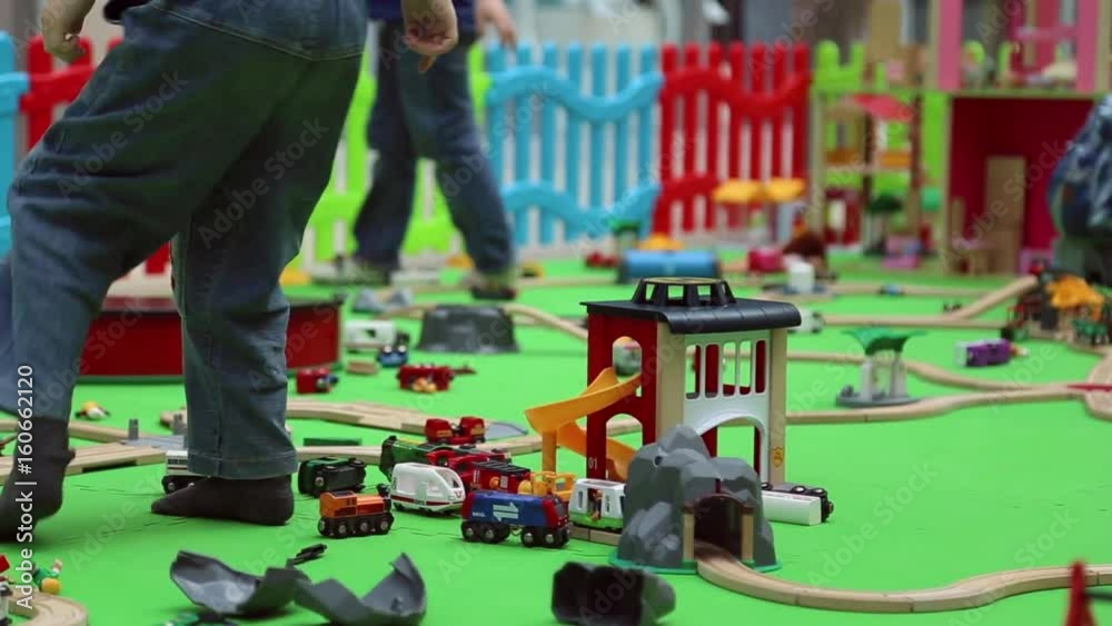 A boy plays on children's educational playground with toy cars and trains