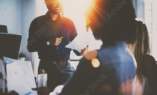 Teamwork concept.Hispanic businessman talking with two colleague woman.Young team of coworkers making great meeting discussion in modern sunny office.Closeup horizontal,blurred background.
