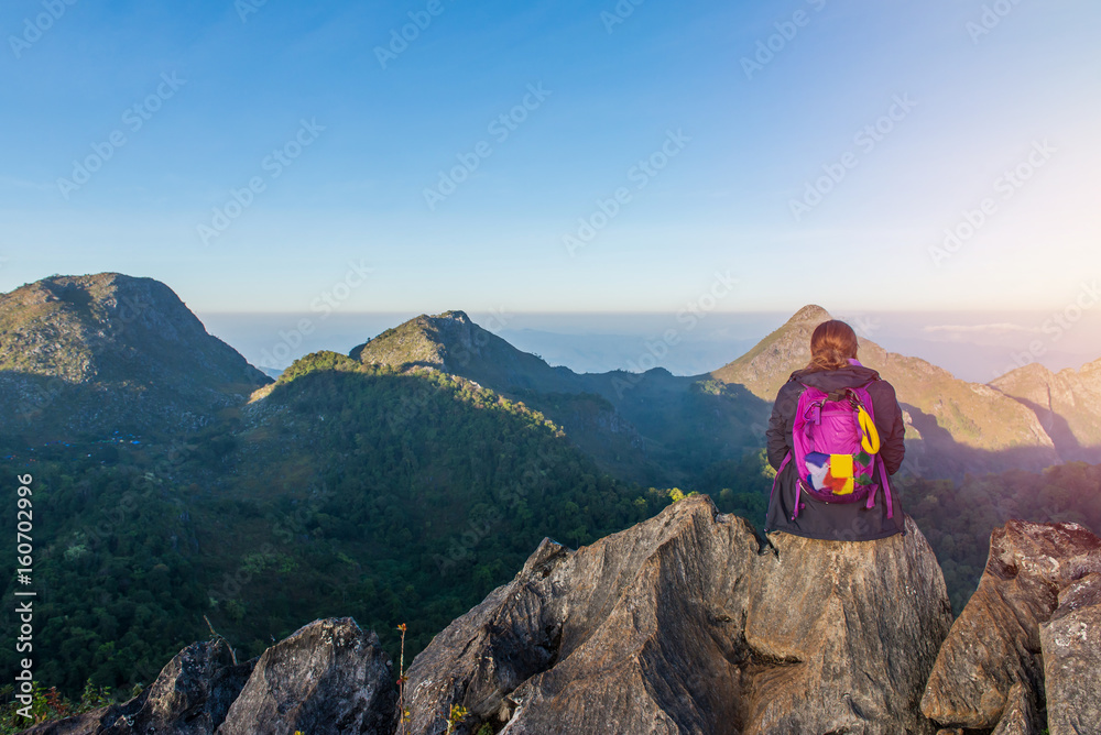 Woman on top of mountain sitting on the rock watching a view landscape at Doi Luang Chiang Dao, ChiangMai Thailand.