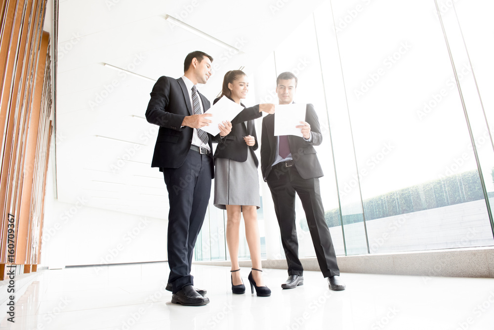 Business people discussing documents in building hallway Business people discussing documents in building hallway