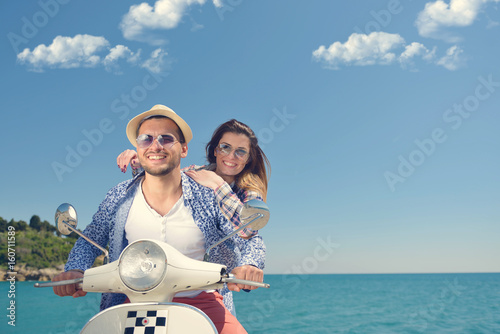 Beautiful young couple in love enjoying and having fun riding on a scooter in a beautiful nature