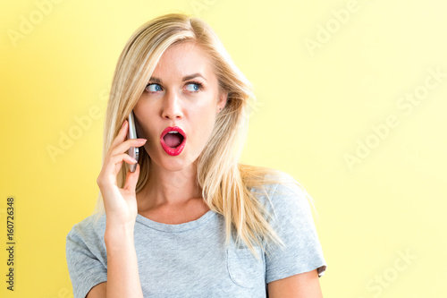 Young woman talking on the phone on a yellow background