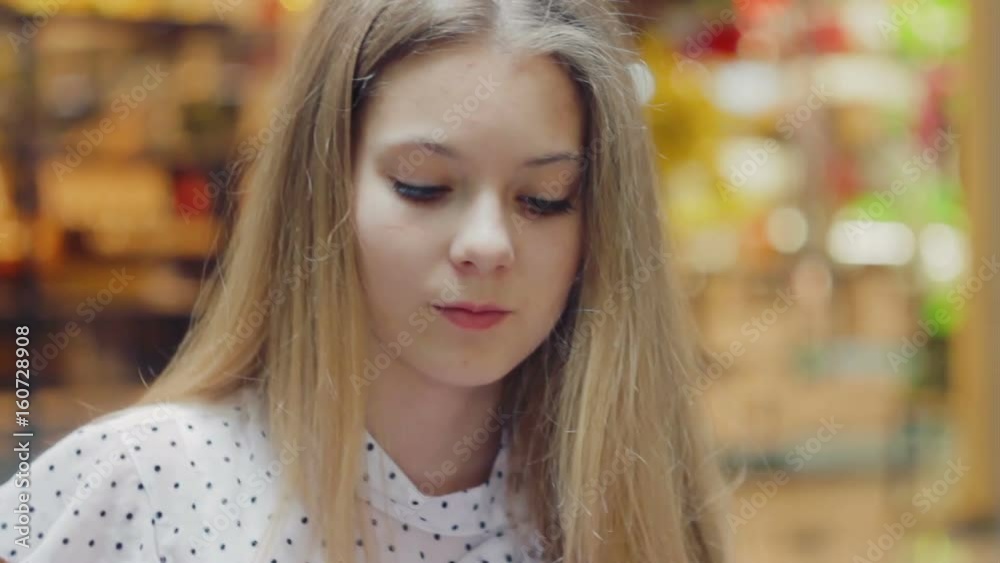 Sweet girl 13 years old sitting on the couch in the mall playing in the smartphone in the game