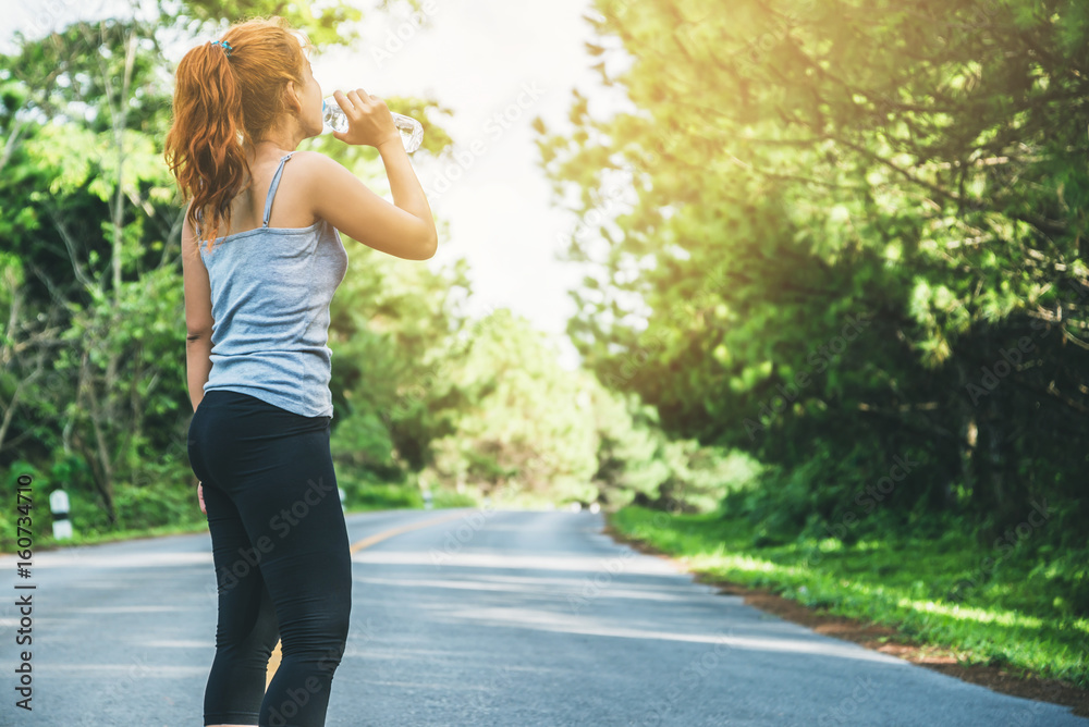 Women exercise on the street. Nature park. Drink healthy water. Asian women Women exercise on the street. Nature park. Drink healthy water. Asian women