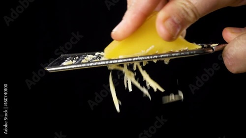 Hand bubbing the cheese on metal grater on black background