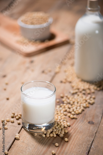 Soy milk or soya milk and soy beans in spoon on wooden table.