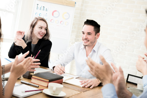 Business people clapping hands to congratulate  their colleague at the meeting photo