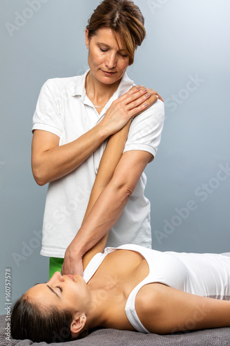 Female osteopath manipulating arm on patient.