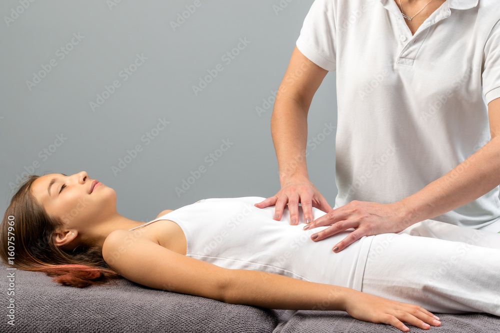 Fototapeta premium Therapist doing abdomen massage on little girl.