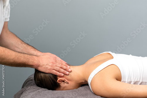 Therapist applying pressure on back of female head.