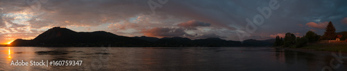 The sun if coming up and more lights by the river with cloudy clouds