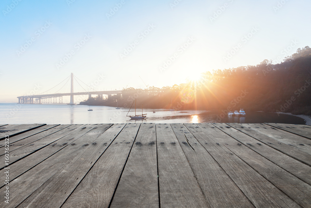 empty wooden floor near modern suspension bridge with sunbeam