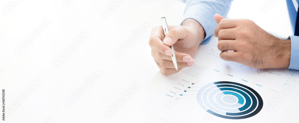 Businessman holding pen while reading statistic graph on white working table - obrazy, fototapety, plakaty 