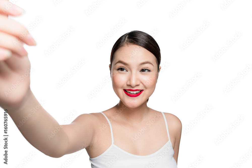 Beautiful asian woman with retro makeup with red lips taking selfie photo isolated on white background. Beautiful asian woman with retro makeup with red lips taking selfie photo isolated on white background.