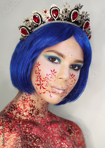 Young girl model in the art make-up like princess in a crown from fairytail looking at camera with blue hair photo