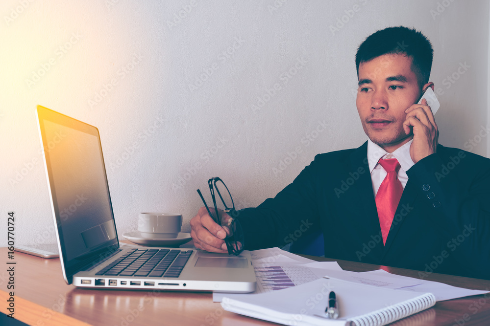 Business man working at office with smart phone and documents on his desk