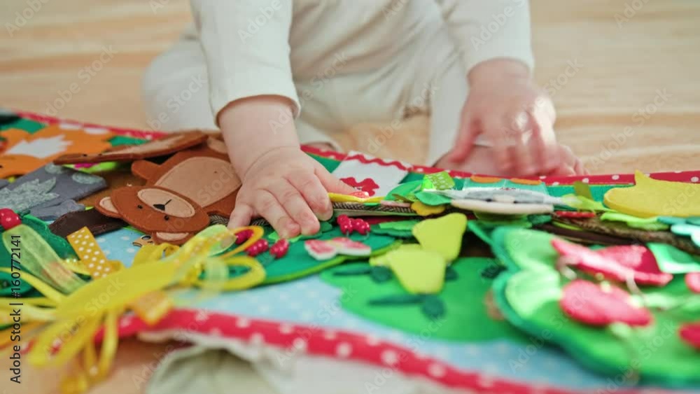 Baby sitting on the bed and playing with toys. Close-up shot of baby's hands and feet. Soft focus Baby sitting on the bed and playing with toys. Close-up shot of baby's hands and feet. Soft focus