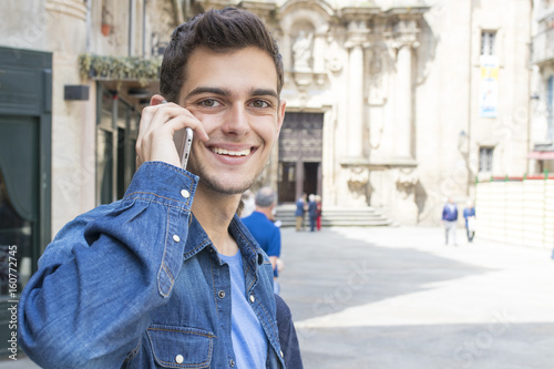 teen young man with the phone in the street of the city